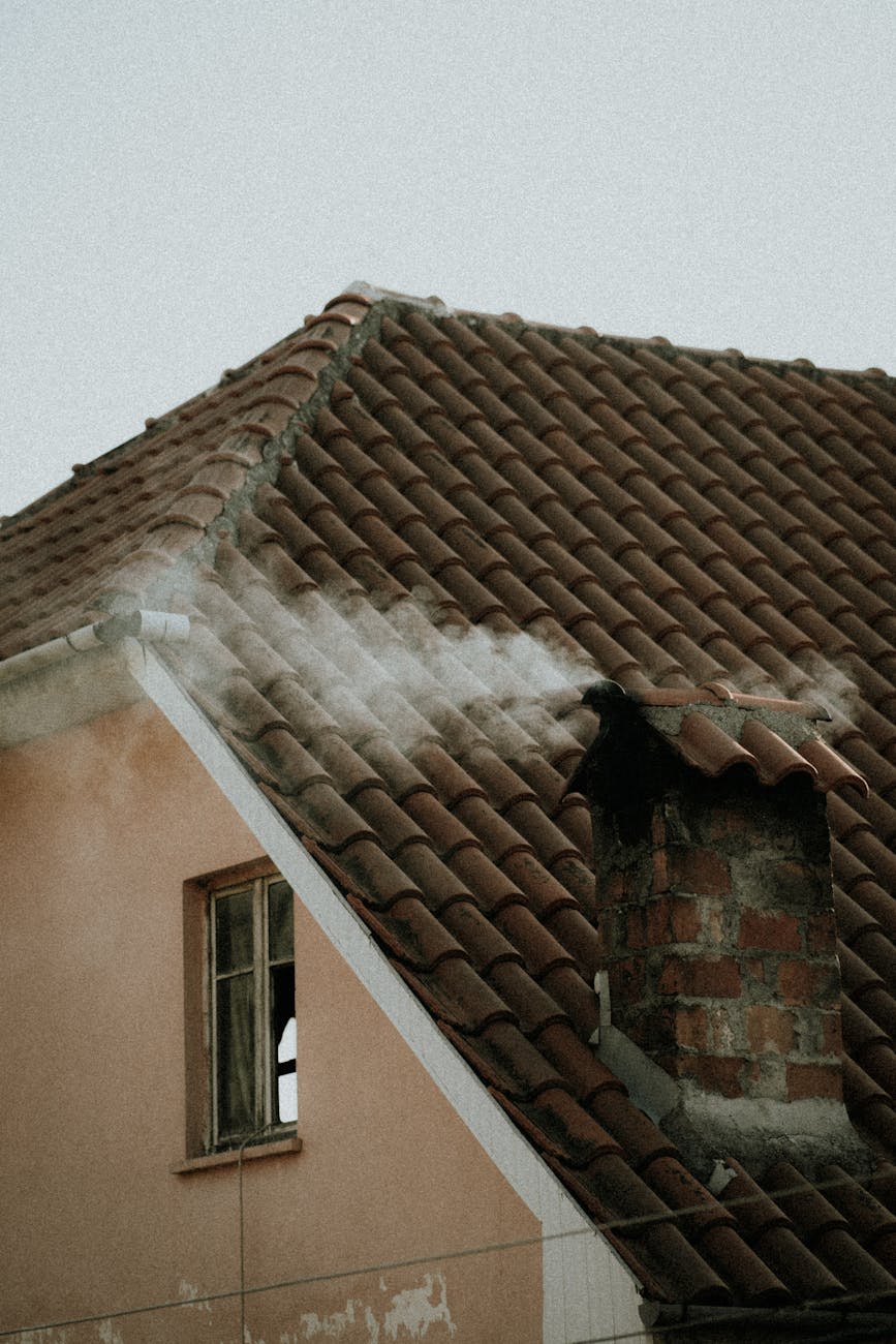 smoke coming out of a brick chimney on a tiled roof